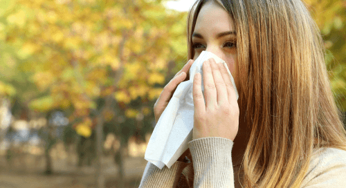 Donna all’aperto che si soffia il naso con un fazzoletto a causa delle allergie di fine estate.