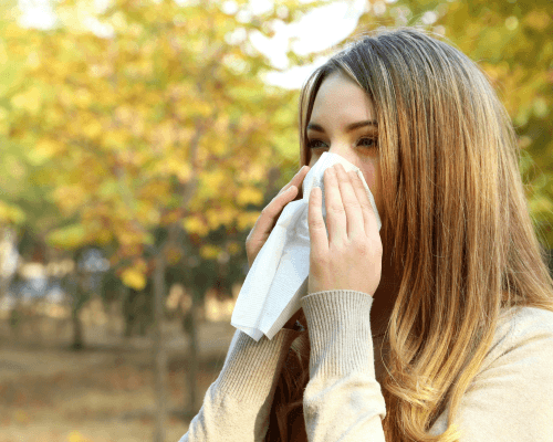 Donna all’aperto che si soffia il naso con un fazzoletto a causa delle allergie di fine estate.