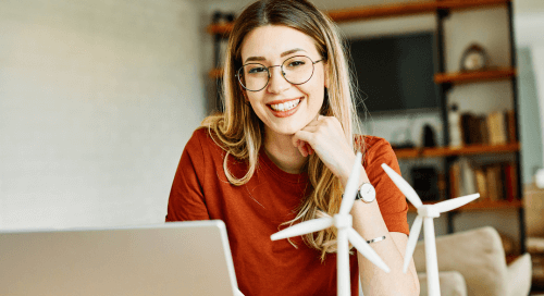 Donna sorridente al computer, pronta a ripartire con energia e motivazione dopo il ritorno alla routine.