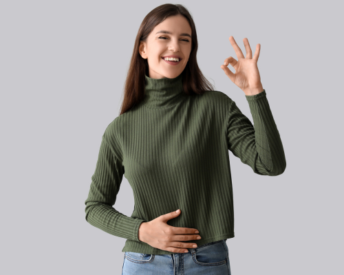 Donna sorridente che tocca la pancia e mostra il gesto “ok” con la mano, simbolo di benessere intestinale e equilibrio del microbiota.
